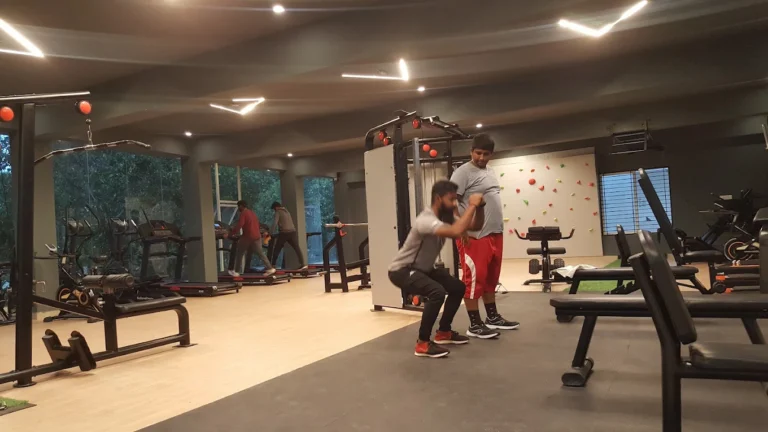 Personal trainer guiding a member through squat exercises for weight loss at Torque Fitness Mysore