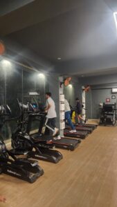 Members using treadmills and stationary cycles in the cardio training zone at Torque Fitness Mysore