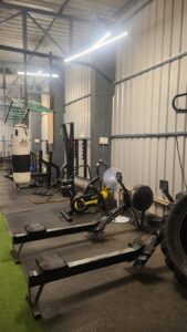 Functional workout area at Torque Fitness with rowing machine, cycling machine, punching bags, large tire, and cardio training equipment